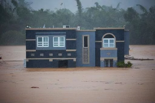 A home is submerged in floodwaters caused by Hurricane Fiona in Cayey, Puerto Rico, Sunday, Sept. 18, 2022.  According to authorities three people were inside the home and were reported to have been rescued.  (AP Photo/Stephanie Rojas)