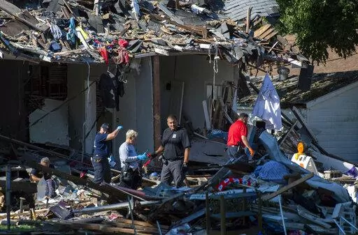 Emergency personnel search the debris, Thursday, Aug. 11, 2022, in  Evansville, Ind., as authorities work to determine the cause of a house explosion that killed three people and left another person hospitalized. The explosion the day before damaged 39 homes. (MaCabe Brown/Evansville Courier & Press via AP)