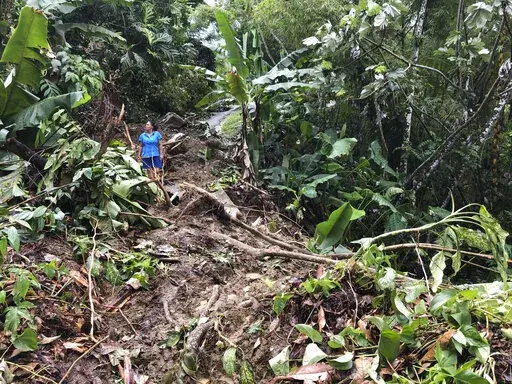 Nancy Galarza looks at the damage that Hurricane Fiona inflicted on her community, which remained cut off four days after the Category 1 storm slammed the rural community of San Salvador in the town of Caguas, Puerto Rico, Thursday, Sept. 22, 2022. (AP Photo/Danica Coto)