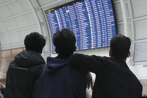 Passengers look up at the departure board as they wait due to a global technology outage at Toronto Pearson Airport, on Friday, July 19, 2024. (Chris Young/The Canadian Press via AP)