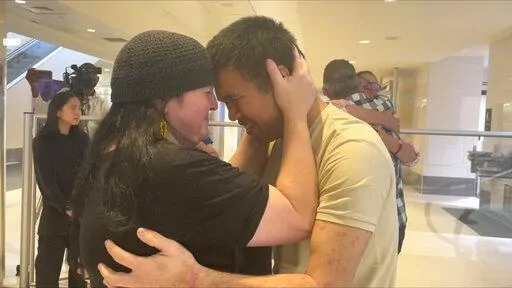 Andy Huynh, left, and Alex Drueke, far right, are seen hugging their loved ones after arriving at Birmingham-Shuttlesworth International Airport in Birmingham, Ala., Saturday, Sept. 24, 2022. The U.S. military veterans disappeared three months ago while fighting Russia with Ukrainian forces. They were released earlier this week by Russian-backed separatists as part of a prisoner exchange. (AP Photo/Kim Chandler)