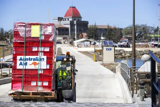 In this photo provided by the Australian Defence Force, la loader is used to move aid supplies at the port at Nuku'alofa, Tonga, Thursday, Jan. 27, 2022, after HMAS Adelaide carried in the disaster relief and humanitarian aid supplies. The danger of spreading the coronavirus was underscored when nearly two dozen sailors aboard the the Adelaide were reported infected on Tuesday, raising fears they could bring the coronavirus to the small Pacific archipelago devastated by an undersea volcanic erup