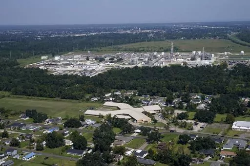 The Fifth Ward Elementary School and residential neighborhoods sit near the Denka Performance Elastomer Plant, back, in Reserve, La., Sept. 23, 2022. The EPA sued Denka Performance Elastomer LLC, arguing that its petrochemical operations in southern Louisiana posed an unacceptable cancer risk to the mostly-Black community nearby. The EPA has demanded that the company reduce toxic emissions from its plant that makes synthetic rubber. (AP Photo/Gerald Herbert, File)