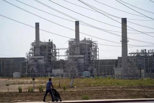 A man pushes a stroller near the AES power plant in Redondo Beach, Calif., Wednesday, Sept. 7, 2022. A record heat wave put California in a fossil fuel conundrum: The state has had to rely more heavily on natural gas to produce electricity and avoid power outages while Gov. Gavin Newsom's administration moves toward ending the use of oil and gas. (AP Photo/Jae C. Hong)