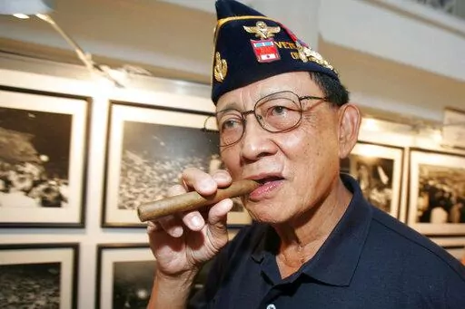Former Philippine President Fidel Ramos bites his cigar as he looks on photographs during an exhibit on the 20th anniversary of "People Power" in suburban Makati, south of Manila, Philippines, on Feb. 22, 2006. Ramos, a U.S.-trained ex-general who saw action in the Korean and Vietnam wars and played a key role in a 1986 pro-democracy uprising that ousted a dictator, has died. He was 94. Some of Ramos's relatives were with him when he died on Sunday, July 31, 2022, said his longtime aide Norman L