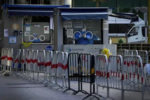 Workers in protective gear wait to administer a COVID-19 test at a quiet coronavirus testing site in Beijing, Sunday, Dec. 11, 2022. Facing a surge in COVID-19 cases, China is setting up more intensive care facilities and trying to strengthen hospitals as Beijing rolls back anti-virus controls that confined millions of people to their homes, crushed economic growth and set off protests. (AP Photo/Andy Wong)
