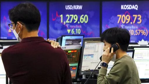 A currency trader talks on the phone near a screen showing the foreign exchange rate between U.S. dollar and South Korean won, center, at a foreign exchange dealing room in Seoul, South Korea, Thursday, Dec. 22, 2022. Shares advanced in Asia on Thursday after a rally on Wall Street as investors welcomed a report showing U.S. consumer confidence is holding up despite the Federal Reserve’s campaign to fight inflation by raising interest rates. (Choi Jin-suk/Newsis via AP)