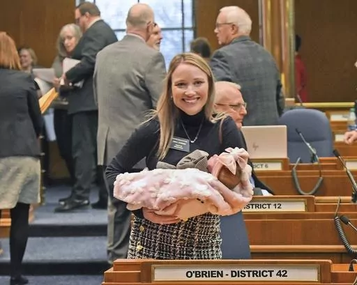 Rep. Emily O'Brien R-Grand Forks carries daughter Jolene Green, 3 weeks, into the House chamber, Dec. 6, 2022, in Bismarck, N.D. Last year, the state representative helped persuade her colleagues to approve $66 million in child care spending proposed by Gov. Doug Burnum, a Republican. O'Brien argued it could help the state's workforce shortage by helping more parents go to work. (Tom Stromme/The Bismarck Tribune via AP)