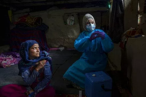 Masrat Farid, a healthcare worker, prepares to administer a dose of Covishield vaccine to Rubia Begum inside a hut during a COVID-19 vaccination drive in Gagangeer, northeast of Srinagar, Indian controlled Kashmir on June 22, 2021. Farid has traveled long distances to vaccinate mostly shepherds and nomadic herders in the remote meadows of the Himalayan region of Indian-controlled Kashmir. (AP Photo/Dar Yasin)