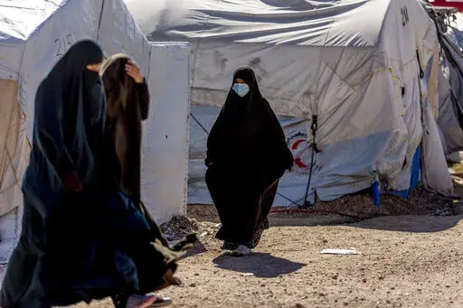 Women walk in Roj detention camp in northeast Syria Wednesday, Feb. 9, 2022. Syrian Kurdish authorities are struggling to supervise tens of thousands of IS-affiliated foreign nationals they are holding in camps and prisons across northeast Syria, with no one to take them. A deadly prison attack last month has sharpened the focus on the detainees' uncertain future. (AP Photo/Baderkhan Ahmad)
