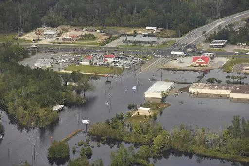 In this Monday, Sept. 24, 2018 photo, flood waters from the Neuse River cover the area a week after Hurricane Florence in Kinston, N.C. Monday Sept. 24, 2018.  Hot real estate markets have made some homeowners wary of participating in voluntary flood buyout programs, impacting efforts to move people away from flooding from rising seas, intensifying hurricanes and more frequent storms.  Flood buyout programs typically purchase flood-prone homes, raze them and turn the property into green space. (