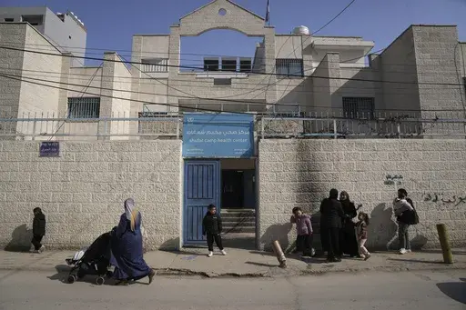 Palestinians gather outside of a health clinic run by the United Nations agency for Palestinian refugees, known as UNRWA, in the Shuafat refugee camp in Jerusalem, Monday, Jan. 27, 2025. (AP Photo/Mahmoud Illean)