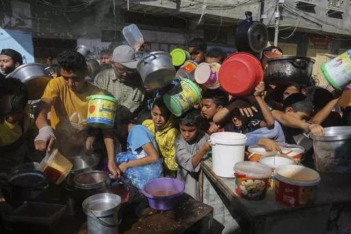 Palestinians crowd together as they wait for food distribution in Rafah, southern Gaza Strip, Nov. 8, 2023. Catastrophic hunger is so dire in two world hotspots that famine is imminent in northern Gaza and approaching in Haiti, with hundreds of thousands of people in both places struggling to avoid starvation, according to international food security experts and aid groups. (AP Photo/Hatem Ali, File)