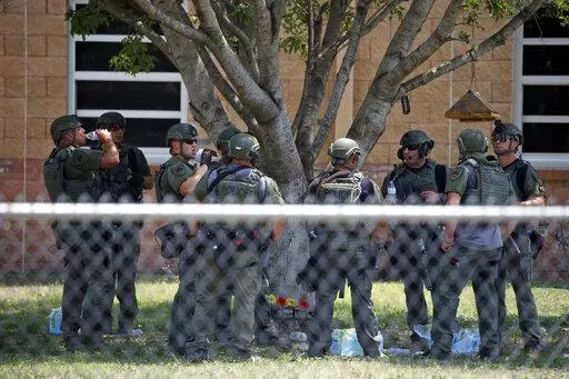 Law enforcement personnel stand outside Robb Elementary School following a shooting, May 24, 2022, in Uvalde, Texas. When the gunman arrived at the school, he hopped its fence and easily entered through an unlocked back door, police said. He holed himself up in a fourth-grade classroom where he killed the children and teachers. (AP Photo/Dario Lopez-Mills, File)