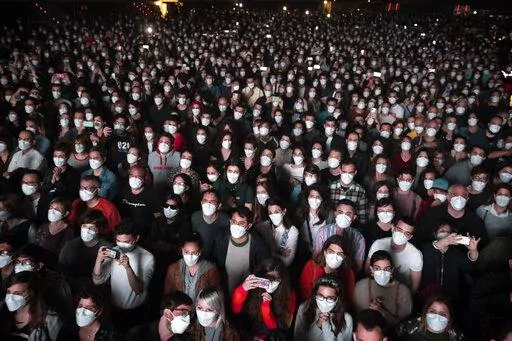 People using face masks attend a music concert in Barcelona, Spain, March 27, 2021. With one of Europe's highest vaccination rates and its most pandemic-battered economies, the Spanish government is laying the groundwork to approach the virus in much the same way countries deal with flu or measles. (AP Photo/Emilio Morenatti, File)