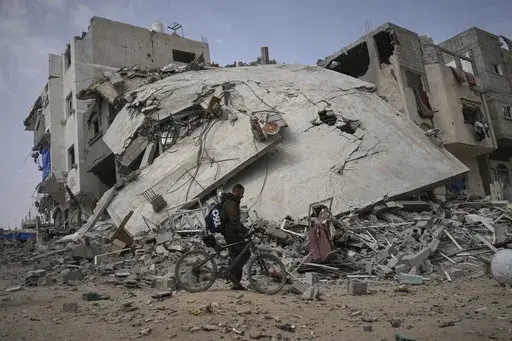 A man passes by the destroyed house of journalist Islam Meqdad, where she was killed along with her son and five other family members in an Israeli army strike in Khan Younis, southern Gaza Strip, Sunday, April 6, 2025. (AP Photo/Abdel Kareem Hana)