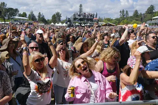 In this May 26, 2018, file photo, people listen to Michael Franti perform at the BottleRock Napa Valley music festival in Napa, Calif.  Summer music festivals can be a once-in-a-lifetime experience, but costs can be excessive for many fans. With expenses for food, drinks, outfits, flights and hotels on top of the ticket price, budgeting for a festival can outperform even the best lineups. Taking advantage of credit card rewards for entertainment purchases, planning ahead for hidden costs, using 