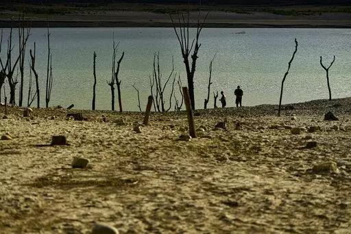 People walk close to the border at Yesa's reservoir affected by drought, on a sunny summer day in Yesa, around 55 kilometers (34,17 miles), from Pamplona, northern Spain, Sept. 14, 2022. Widespread drought that dried up large parts of Europe, the United States and China this past summer was made 20 times more likely by climate change, according to a new study. (AP Photo/Alvaro Barrientos)