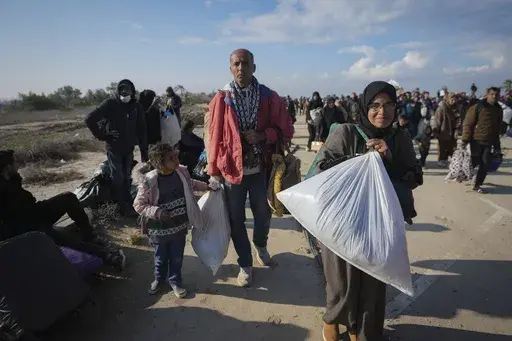 Ne'man Abu Jarad, center, and his wife Majida, center right, walk with their children as thousands of displaced Palestinians return to their homes in the northern Gaza Strip, following Israel's decision to allow them to go back for the first time since the early weeks of the 15-month war with Hamas, Monday, Jan. 27, 2025. (AP Photo/Abdel Kareem Hana)