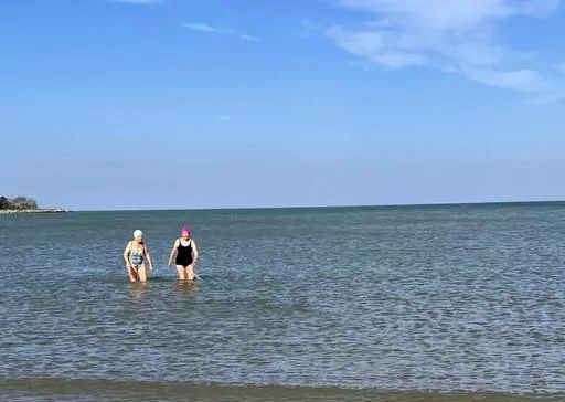 Roberta Rubin, 85, left, and Dorothy Harza, 93, wade in the water after a late-autumn swim in Lake Michigan on Nov. 10, 2022, in Evanston, Ill. Harza swims nearly daily in Lake Michigan from May to November. (Roberta Rubin via AP)