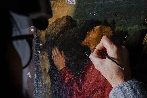 Restorer Valentina Piovan works on Vittore Carpaccio's 1502 painting 'The agony in the garden' at the Dalmatian School in Venice, northern Italy, Wednesday, Dec. 7, 2022. On November 20th, the National Gallery of Washington inaugurated the first retrospective exhibition of Carpaccio’s works outside of Italy. It will run until February 12, 2023. (AP Photo/Domenico Stinellis)