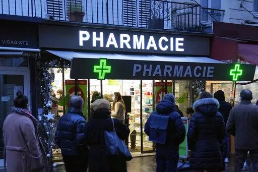 People wait in front of a pharmacy to get a COVID-19 test in Paris, France, Sunday, Jan. 9, 2022. On Friday, Dec. 9, 2022, President Emmanuel Macron announced France will make condoms free in pharmacies for anyone up to age 25 in the new year. (AP Photo/Francois Mori, File)