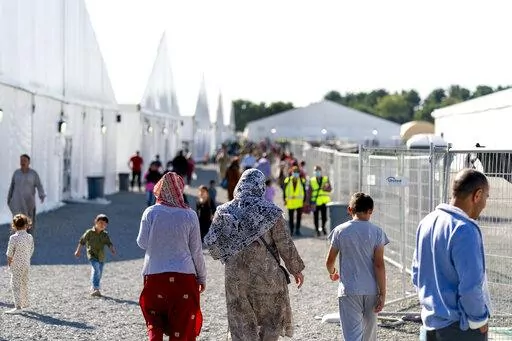 Afghan refugees walk through an Afghan refugee camp at Joint Base McGuire Dix Lakehurst, N.J., on Sept. 27, 2021. The last of thousands of Afghan refugees who awaited resettlement at eight U.S. military installations departed from the New Jersey base on Saturday, Feb. 19, 2022. They are completing a journey that started with the chaotic evacuation from Kabul in August. (AP Photo/Andrew Harnik, File)