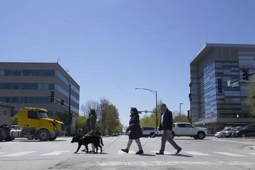 Maureen Reid, left, and her guide dog, Gaston, cross the intersection of Wood Street and Roosevelt Avenue with Sandy Murillo, center, and Geovanni Bahena, relying on an audible signal for the blind, on April 26, 2023, in Chicago. Faced with a growing backlash, the U.S. Census Bureau said Tuesday, Feb. 6, 2024, that it is pausing plans to change how it asks people about disability in its most comprehensive survey, a move that would have overhauled how disabilities are defined by the nation's larg