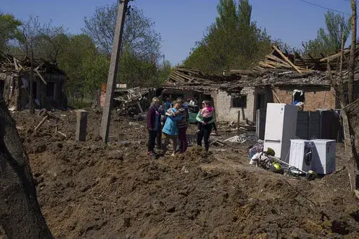 People react as they stand next to a crater in destroyed residential area after Russian airstrike in Bakhmut, Donetsk region, Ukraine, Saturday, May 7, 2022. (AP Photo/Evgeniy Maloletka)