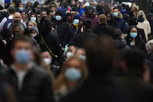 Shoppers walk down Oxford Street, Europe's busiest shopping street, in London, Dec. 23, 2021. The British government confirmed Saturday Feb. 19, 2022, that people with the coronavirus will not be legally required to self-isolate starting next week, as part of a plan for “living with COVID” that is also likely to see testing for the virus scaled back. (AP Photo/Frank Augstein, File)