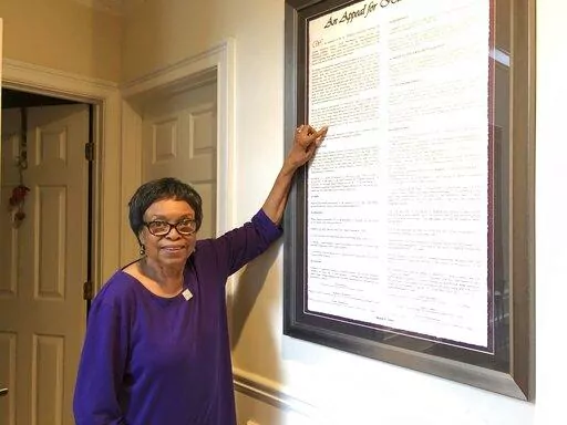 In this March 4, 2020 photo, Roslyn Pope poses with a framed copy of "An Appeal for Human Rights" in her home in Atlanta. Roslyn Pope, a college professor and musician who wrote “An Appeal for Human Rights,” laying out the reasons for the Atlanta Student Movement against systemic racism in 1960, has died. She was 84. Pope died on Jan. 18 in Arlington, Texas, where she moved from Atlanta to be with her daughters after her health began to fail in 2021, according to her family's obituary. (AP P