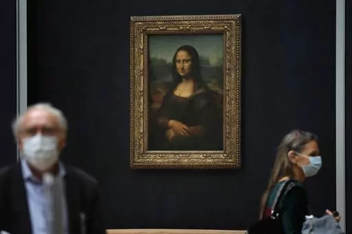 Journalists walk past Leonardo da Vinci's Mona Lisa during a visit of the Louvre museum Tuesday, June 23, 2020. Using X-rays to peer into the chemical structure of a tiny speck of the celebrated work of art, scientists have gained new insight into the techniques that Leonardo da Vinci used to paint his groundbreaking portrait of the woman with the exquisitely enigmatic smile. (AP Photo/Christophe Ena, File)