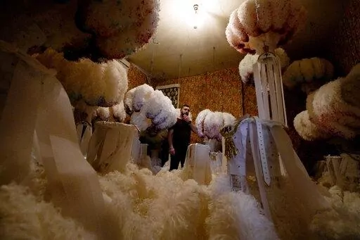 Quentin Kersten stands in the middle of a room full of ostrich feather hats in the Kersten family costume workshop in Binche, Belgium, Wednesday, Feb. 1, 2023. After a COVID-imposed hiatus, artisans are putting finishing touches on elaborate costumes and floats for the renowned Carnival in the Belgian town of Binche, a tradition that brings together young and old and is a welcome moment of celebration after a rough few years. (AP Photo/Virginia Mayo)