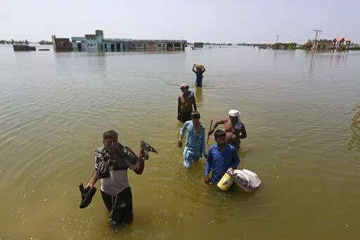 Victims of flooding from monsoon rains carry belongings salvaged from their flooded home in the Dadu district of Sindh Province, of Pakistan, Sept. 9, 2022. Ten years ago scientists warned the world about how climate change would amplify extreme weather disasters. There are now deadly floods, oppressive heat waves, killer storms, devastating droughts and what scientists call unprecedented extremes as predicted in 2012. (AP Photo/Fareed Khan, File)