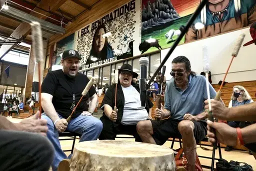 Mark Erickson, third from left, leads others in singing on the drum during an open drum and dance night at Minneapolis American Indian Center on Wednesday, July 10, 2024, in Minneapolis, Minn. (AP Photo/Mark Vancleave)