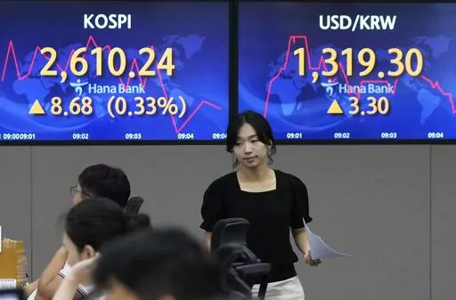 A currency trader passes by the screens showing the Korea Composite Stock Price Index (KOSPI), top left, and the foreign exchange rate between U.S. dollar and South Korean won at the foreign exchange dealing room of the KEB Hana Bank headquarters in Seoul, South Korea, Friday, Aug. 11, 2023. Asian stock markets declined Friday after U.S. inflation edged higher, fueling unease about the outlook for the biggest global economy. (AP Photo/Ahn Young-joon)