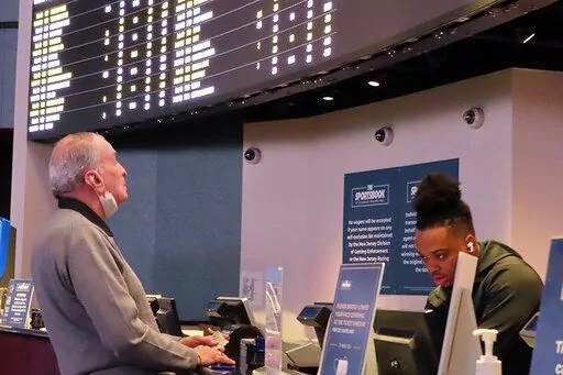 A man places a bet at the sportsbook at the Ocean Casino Resort, on Thursday, Feb. 10, 2022, in Atlantic City, N.J. The American Gaming Association estimates more than 31 million Americans will bet on this year's Super Bowl NFL football game. (AP Photo/Wayne Parry)