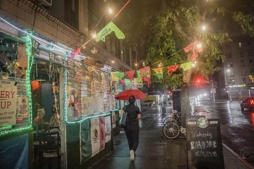A restaurant's pandemic-era outdoor dining, left, extends onto a sidewalk in Brooklyn's Flatbush neighborhood, Monday Aug. 7, 2023, in New York. New York City's roadway dining sheds, a pandemic innovation, are coming under new rules for design and seasonality. (AP Photo/Bebeto Matthews)