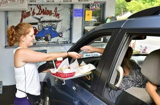  In this Tuesday June 23, 2015 photo, Jim's Drive-In waitress Aly King delivers an order to a waiting customer at the iconic restaurant in Lewisburg, W.Va. A program offering $20,000 in cash and incentives for remote workers to move to West Virginia as part of a population push has chosen 33 people for its second class of newcomers to live in the Greenbrier Valley, which includes Lewisburg. (Bob Wojcieszak/Daily Mail via AP, File)