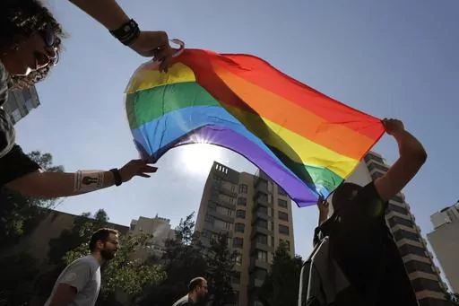 Activists from the Lesbian, Gay, Bisexual, and Transgender (LGBTQ) community in Lebanon shout slogans and hold up a rainbow demanding rights during a protest in Beirut, Lebanon, June 27, 2020. (AP Photo/Hassan Ammar, File)