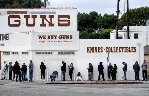 In this March 15, 2020 file photo people wait in a line to enter a gun store in Culver City, Calif. The man who shot and killed four people this week at a Tulsa, Okla., hospital bought his AR-style semiautomatic rifle just hours before he began the killing spree. That would not have been possible in Washington and a half dozen other states that have waiting periods of days or even more than a week before people can take possession of such weapons. (AP Photo/Ringo H.W. Chiu, File)