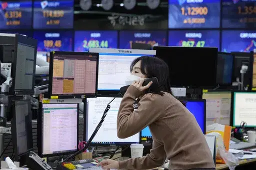 A currency trader talks on the phone at the foreign exchange dealing room of the KEB Hana Bank headquarters in Seoul, South Korea, Thursday, Feb. 24, 2022. Asian stock markets followed Wall Street lower Thursday as anxiety about a possible Russian invasion of Ukraine rose. (AP Photo/Ahn Young-joon)