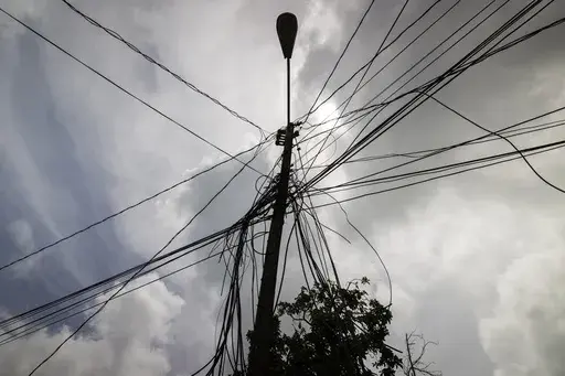 A utility pole with loose cables towers over a home in Loiza, Puerto Rico, Sept. 15, 2022. (AP Photo/Alejandro Granadillo, File)