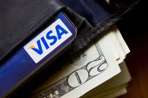 In this Feb. 2, 2011, file photo, a wallet containing cash and a Visa card is displayed in Surfside, Fla. The requests for tips for service are coming more frequently these days, as cashless payment methods with automated tipping options proliferate at checkout counters. To help make responding to these prompts less awkward, tipping experts offer some guidelines. First, it’s worth knowing that you can always decline to tip in scenarios where limited service was provided. But in service-heavy s