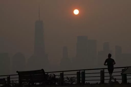 A man runs in front of the sun rising over the lower Manhattan skyline in Jersey City, N.J., June 8, 2023. Thick, smoky air from Canadian wildfires made for days of misery in New York City and across the U.S. Northeast this week. But for much of the rest of the world, breathing dangerously polluted air is an inescapable fact of life — and death. (AP Photo/Seth Wenig, File)