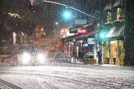 FILE - Motorists navigate downtown Grass Valley, Calif.'s roadways during an early morning snowfall, on, Dec. 14, 2021. Forecasters said Saturday, Dec. 18, 2021, that another round of widespread rain and heavy snow in the mountains is shaping up for recently drenched California and much of Nevada in the coming week and could create hazards for holiday travelers. (Elias Funez/The Union via AP, File)