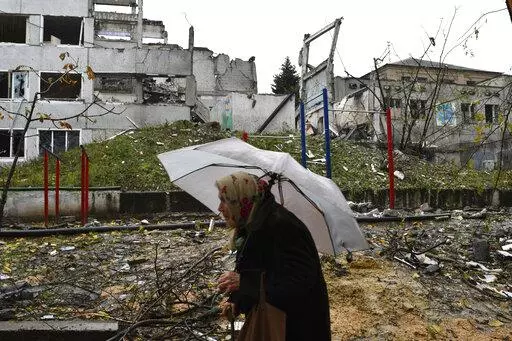 A woman walks past buildings damaged by Russian shelling in Druzhkivka, Donetsk region, Ukraine, Wednesday, Oct. 26, 2022. (AP Photo/Andriy Andriyenko)