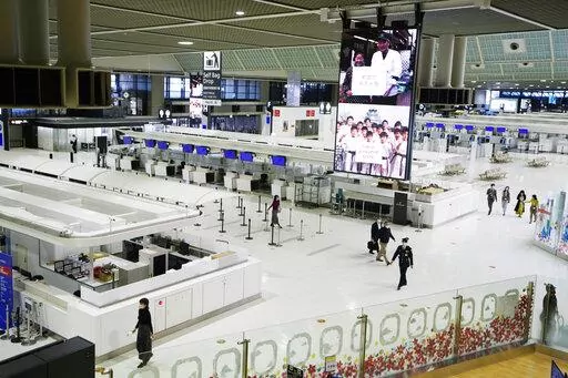 Passengers walk through the ticketing counter floor for international flights at the Narita International Airport in Narita, east of Tokyo, on Dec. 2, 2021. Hundreds of thousands of foreigners have been denied entry to study, work or visit families in Japan, which has kept its doors closed to most overseas visitors during the pandemic. (AP Photo/Hiro Komae, File)