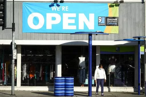 In this June 9, 2021, file photo, a sign announces that a Goodwill store is open in Santa Monica, Calif. Thrifting is hot, and Goodwill finds are cool again. But while we’re thrilled to find the perfect throwback tee for our own closet, gifting used goods still carries a stigma for some. It shouldn’t. Secondhand gifts are better for your wallet, your community and the environment. Buying a thrifted sweatshirt, jacket or vase keeps it from landing in a heap at the dump. (AP Photo/Marcio Jose 