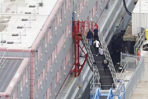 People board the Bibby Stockholm accommodation barge at Portland Port in Dorset, England, Monday, Aug. 7, 2023. A small group of asylum-seekers have been moved to a barge moored in southern England as the government tries to cut the cost of sheltering a rising number of people arriving in the country. British news media reported Monday that the asylum-seekers were transferred to the Bibby Stockholm, a barge stacked with temporary accommodations block that will ultimately house up to 500 men. (Ja